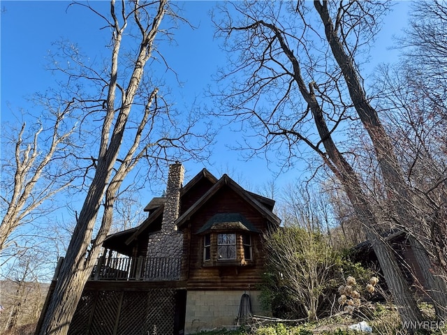 view of side of home featuring log exterior, a chimney, and a deck