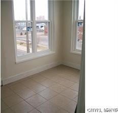 spare room with light tile patterned floors and baseboards
