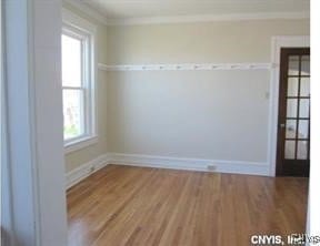 unfurnished room with baseboards, crown molding, and wood finished floors