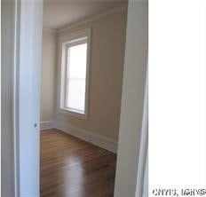 spare room featuring baseboards, ornamental molding, and dark wood-style floors
