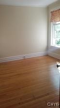 spare room with baseboards and wood finished floors
