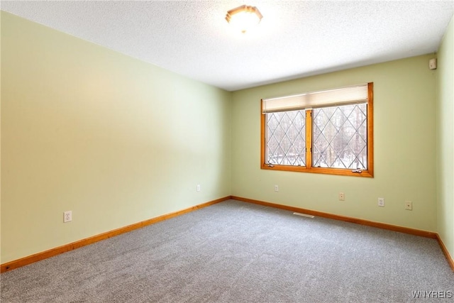 spare room featuring baseboards, carpet flooring, a textured ceiling, and visible vents