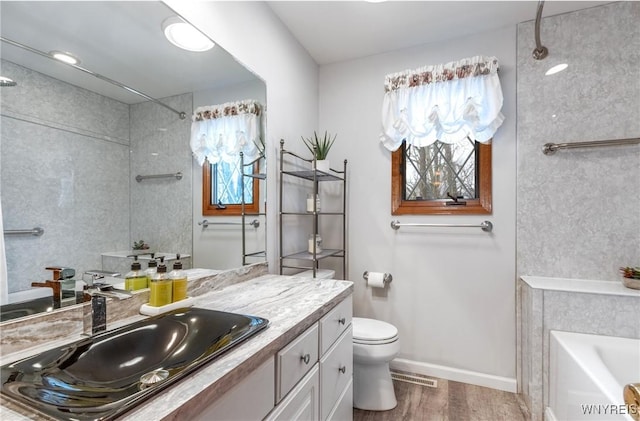 full bath featuring toilet, plenty of natural light, a bathtub, and wood finished floors
