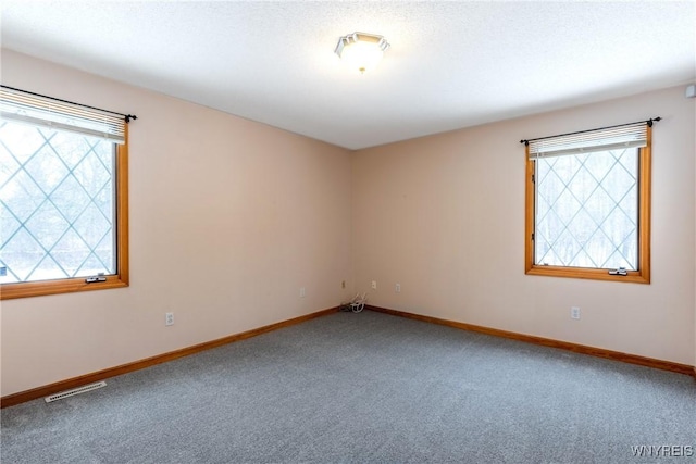 carpeted spare room featuring baseboards and visible vents