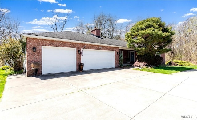 view of side of home featuring a shingled roof, brick siding, a garage, a chimney, and driveway
