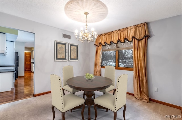 dining room with an inviting chandelier, baseboards, light colored carpet, and visible vents