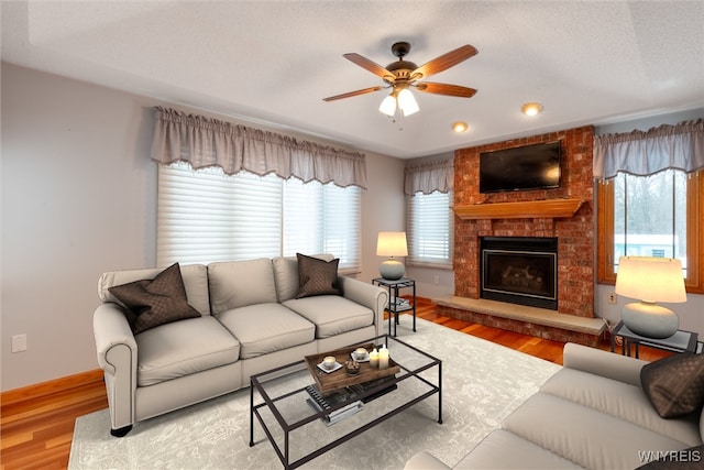 living area with ceiling fan, plenty of natural light, and wood finished floors