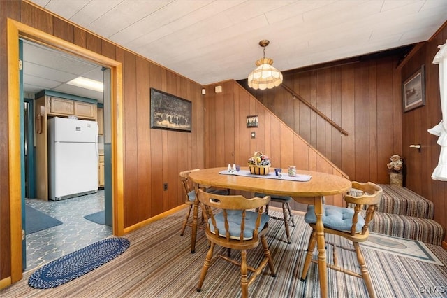 dining space featuring stairway, baseboards, carpet, and wooden walls