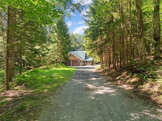 view of street featuring driveway and a wooded view