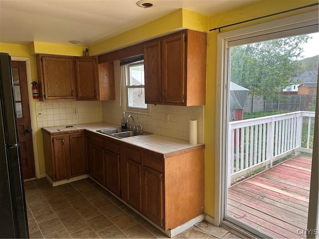 kitchen featuring brown cabinets, tile counters, a sink, and tasteful backsplash