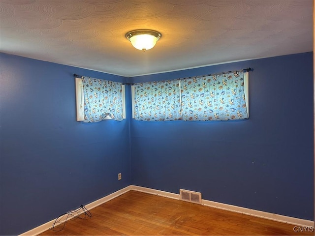 empty room with visible vents, baseboards, and wood finished floors