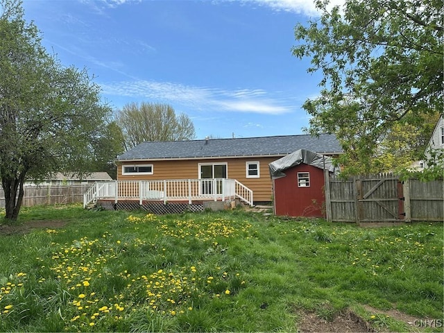 rear view of house featuring a storage shed, an outdoor structure, a wooden deck, and a fenced backyard