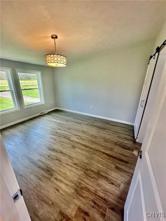 4850 Palmer Rd, Lee, NY 13471 - empty room featuring baseboards, a barn door, and dark wood-type flooring