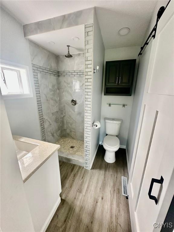4850 Palmer Rd, Lee, NY 13471 - full bath with visible vents, wood finished floors, toilet, baseboards, and tiled shower