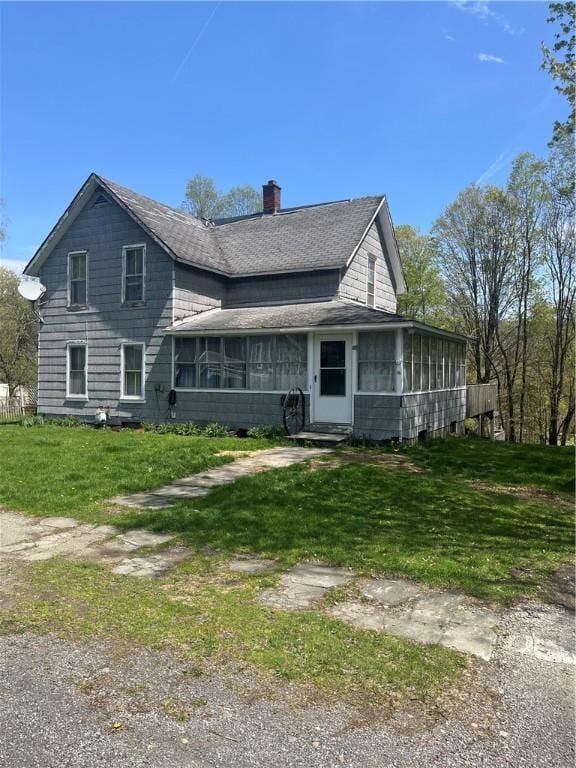 back of property featuring a shingled roof, a yard, a chimney, and a sunroom