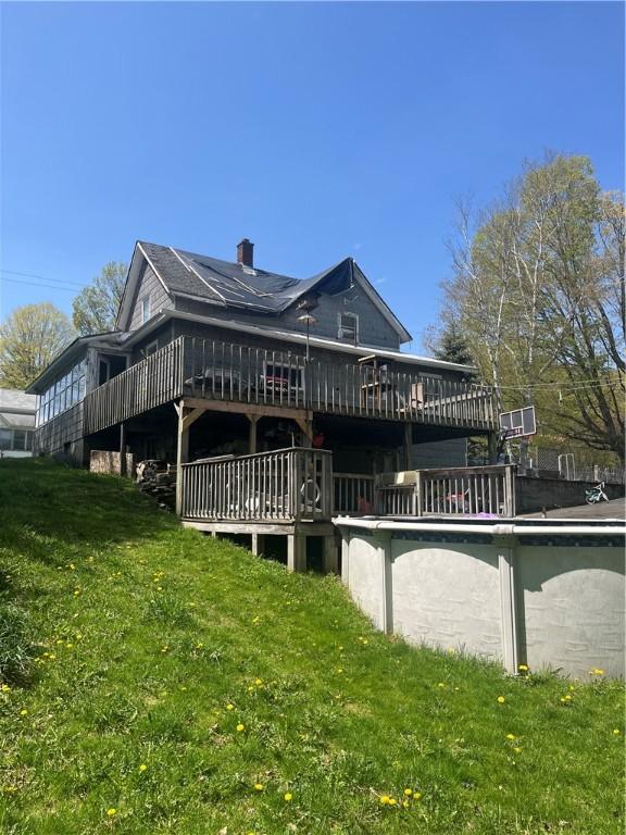 back of property featuring a chimney, a yard, and a deck