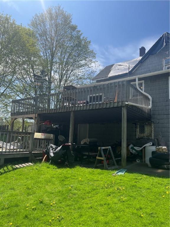 back of property featuring a lawn, a chimney, and a deck