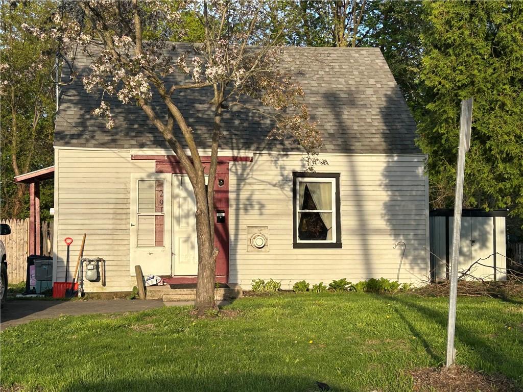 new england style home featuring a shingled roof and a front lawn