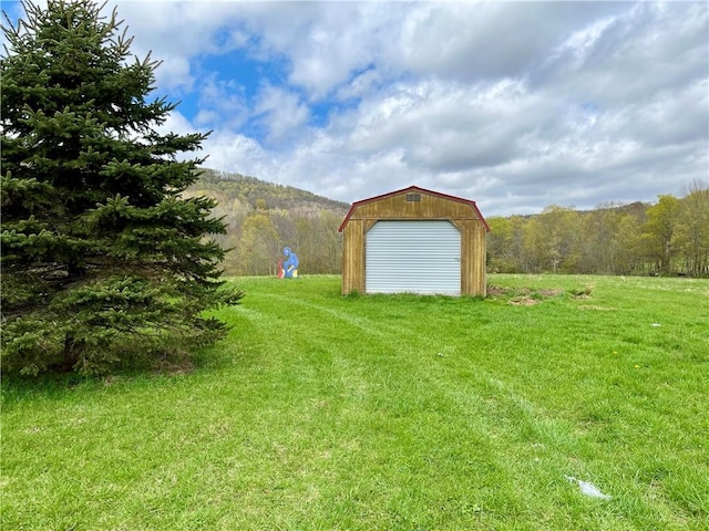 view of yard with an outdoor structure and a wooded view