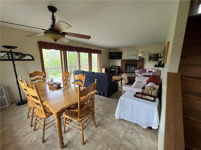 dining space featuring a ceiling fan and a brick fireplace