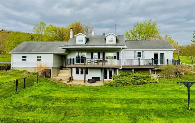 back of property featuring fence, a deck, stairway, a chimney, and a lawn