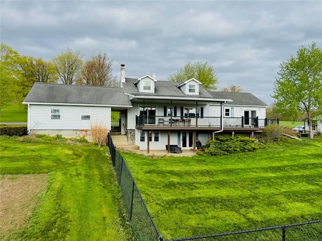back of house with a deck, a chimney, a patio area, a lawn, and fence private yard