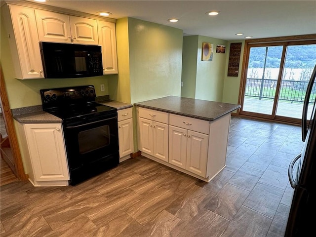 kitchen featuring white cabinets, a peninsula, dark countertops, and black appliances