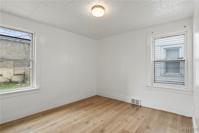 unfurnished room with baseboards, light wood-style flooring, and visible vents