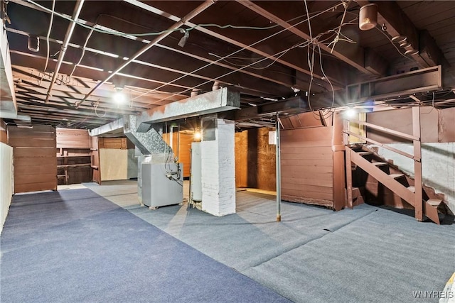 unfinished basement with heating unit, water heater, and stairs