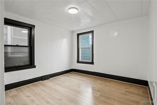 empty room featuring a baseboard radiator and hardwood / wood-style floors