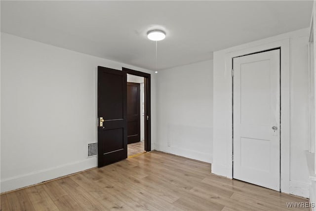 spare room with baseboards, light wood-style flooring, and visible vents