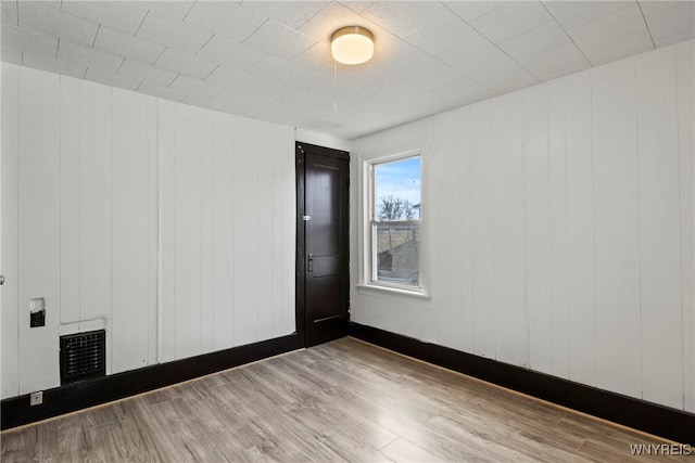 spare room with baseboards, visible vents, and wood finished floors