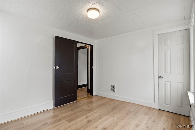 empty room with baseboards, visible vents, and light wood-type flooring