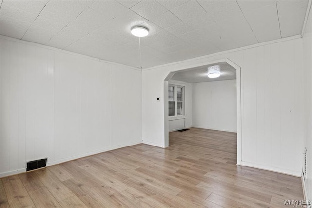 spare room with visible vents, arched walkways, and wood finished floors
