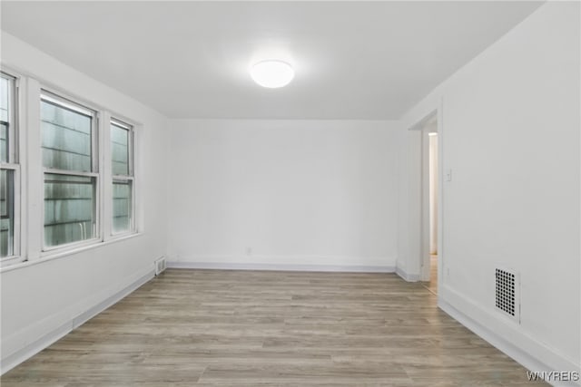 spare room featuring baseboards, light wood-style flooring, and visible vents