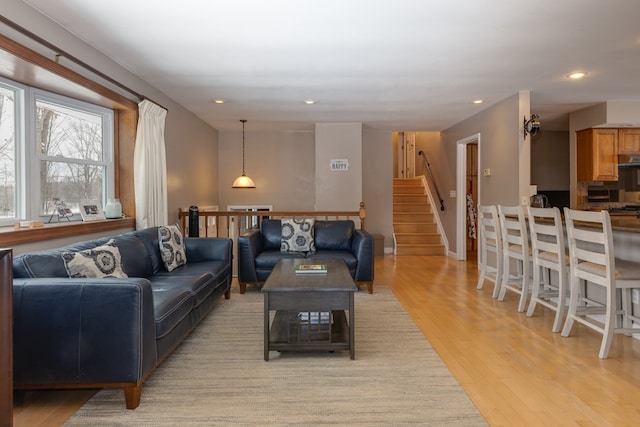 living area with stairs, recessed lighting, baseboards, and light wood-type flooring