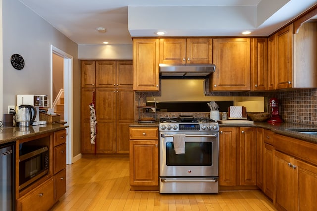 kitchen with light wood-type flooring, under cabinet range hood, brown cabinets, and stainless steel appliances