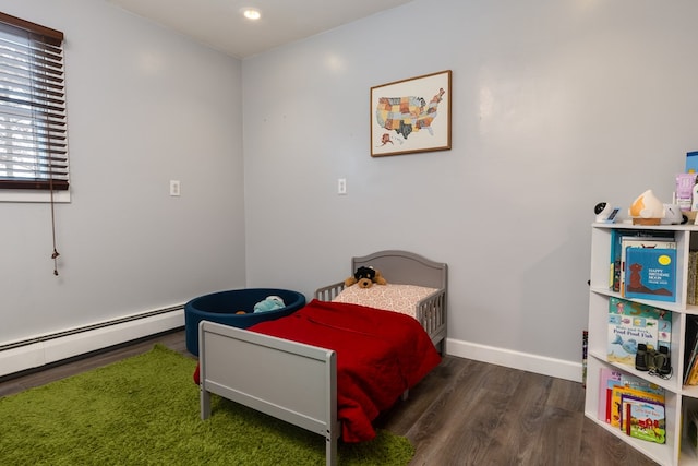 bedroom with baseboards, a baseboard heating unit, and wood finished floors