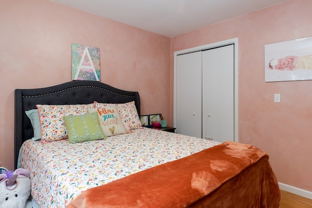 bedroom featuring baseboards, wood finished floors, and a closet