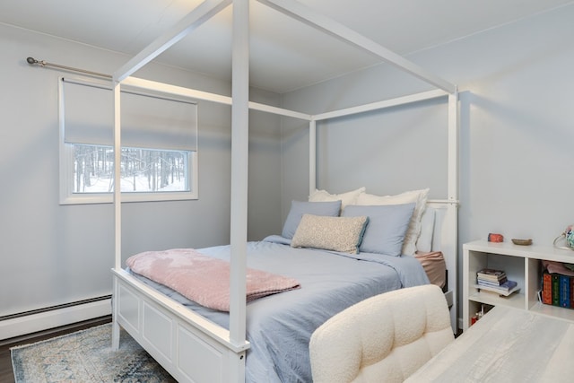 bedroom with baseboard heating and wood finished floors