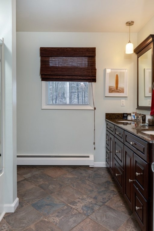 bathroom with double vanity, baseboards, stone finish flooring, and a baseboard radiator