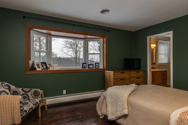 bedroom with visible vents, wood finished floors, baseboards, a baseboard radiator, and ensuite bath