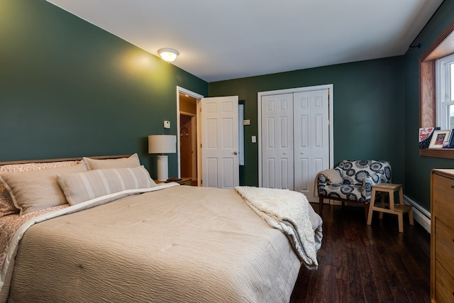 bedroom with dark wood-style flooring, baseboards, baseboard heating, and a closet