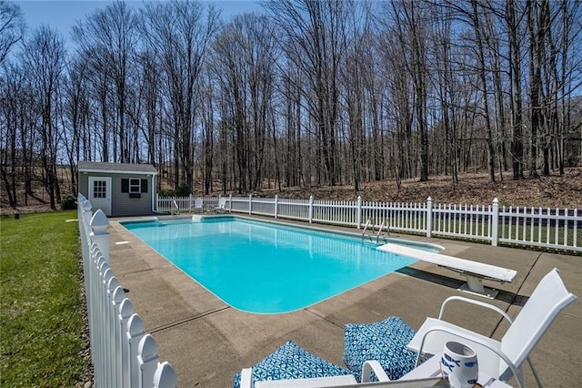 view of swimming pool featuring a diving board, an outbuilding, fence, a fenced in pool, and a yard