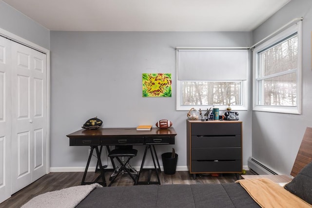 office space featuring wood finished floors, baseboards, and a baseboard heating unit