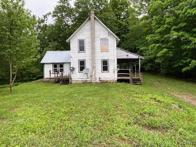 back of house with a yard, a deck, and metal roof