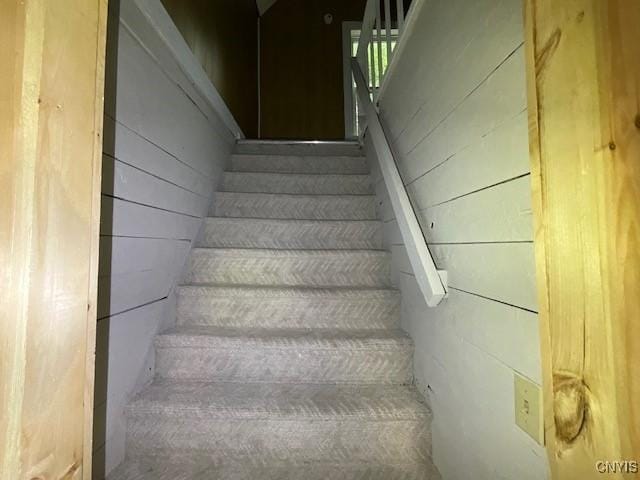 staircase featuring wood walls