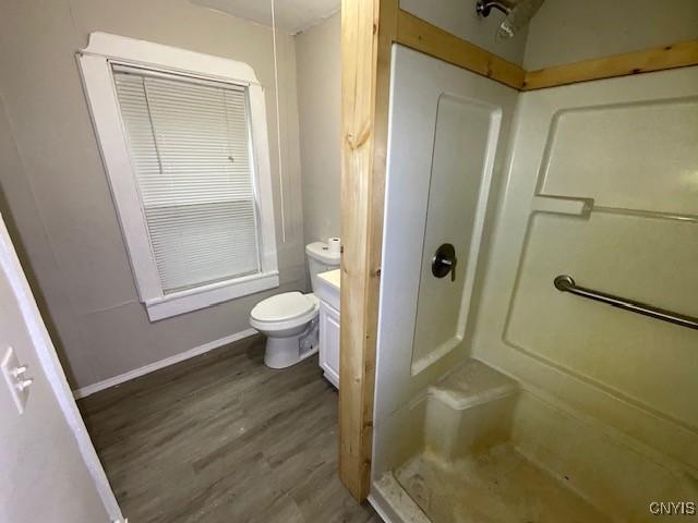 full bath featuring vanity, toilet, baseboards, wood finished floors, and a stall shower