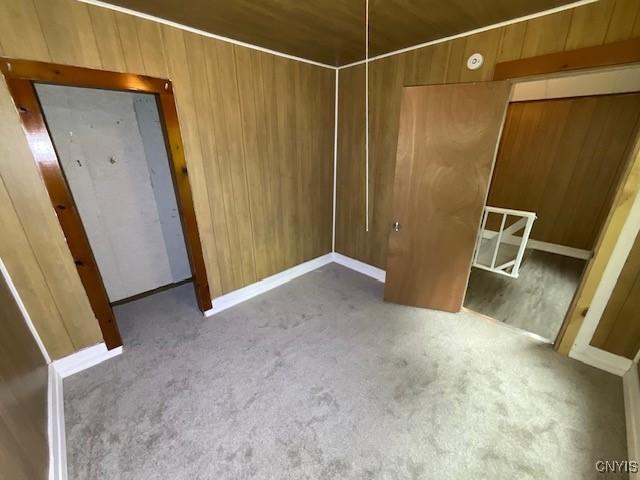 unfurnished bedroom with wood walls, carpet flooring, and wooden ceiling