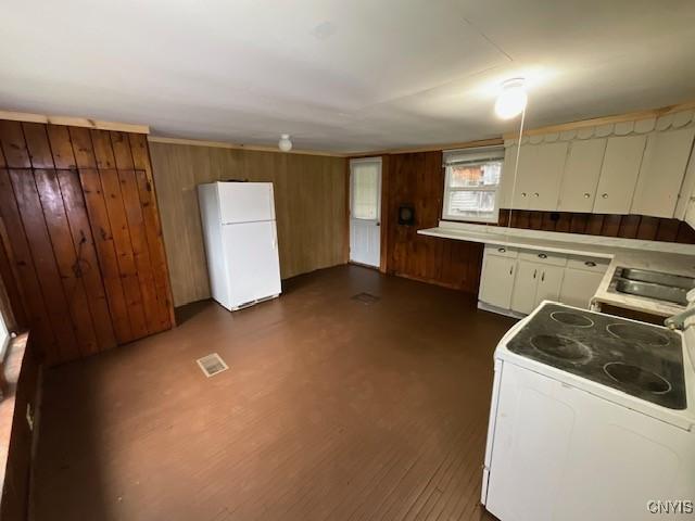 kitchen with visible vents, wood walls, white appliances, light countertops, and white cabinetry